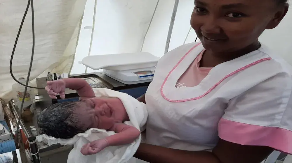 Assisting a mother deliver safely inside a tent in a cyclone-affected locality